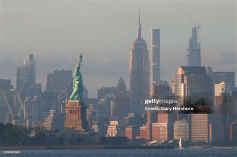 The sun sets on the Statue of Liberty and the Empire State Building ...