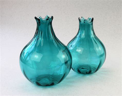 two blue glass vases sitting next to each other