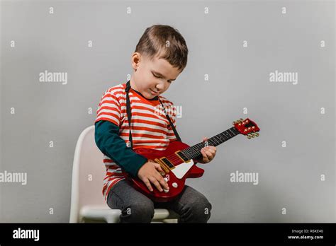 Child playing electric guitar. Portrait of young boy playing children acoustic guitar against ...