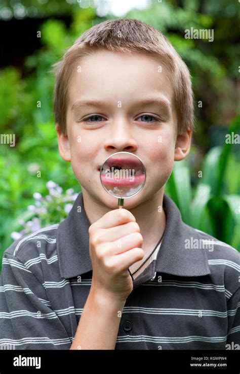 Young boy showing deciduous tooth thru hand magnifier Stock Photo - Alamy
