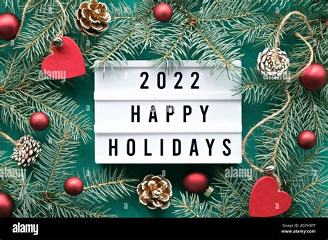 Light board with text 2022 Happy Holidays. Flat lay with fir twigs and ...