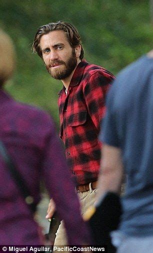 a man wearing a red and black checkered shirt is walking with other men in the background