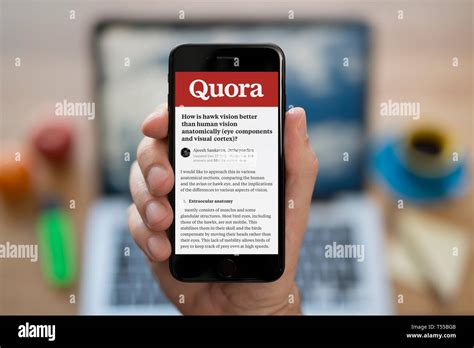 A man looks at his iPhone which displays the Quora logo (Editorial use only Stock Photo - Alamy