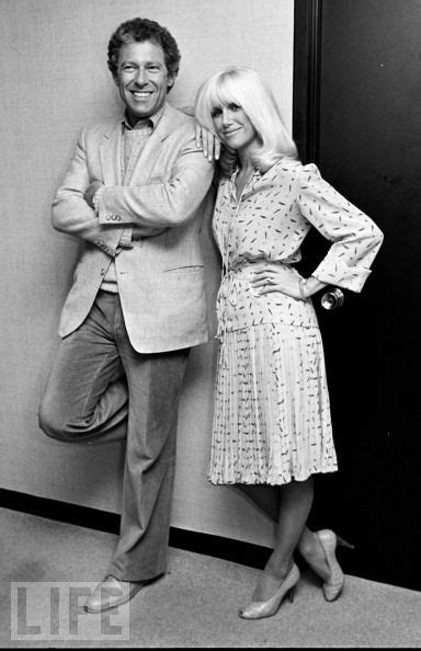 a man and woman standing next to each other in front of a wall with the ...