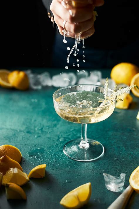 someone is pouring water into a martini glass with lemons on the table ...