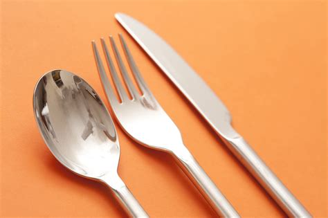 Free Image of Silver Spoon, Fork, and Knife on Orange Background | Freebie.Photography