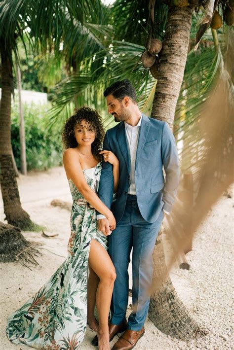 a man and woman standing next to each other under palm trees