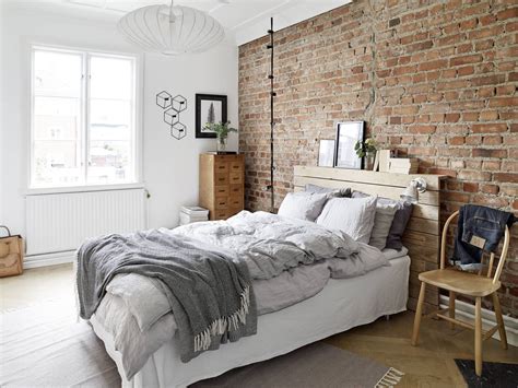 a bedroom with brick wall and white bedding, wooden furniture and rugs on the floor