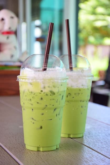 Premium Photo | Iced green tea with straw in plastic cup on table.