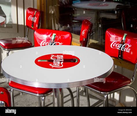 Red coca cola chairs around a white coca cola table Stock Photo - Alamy