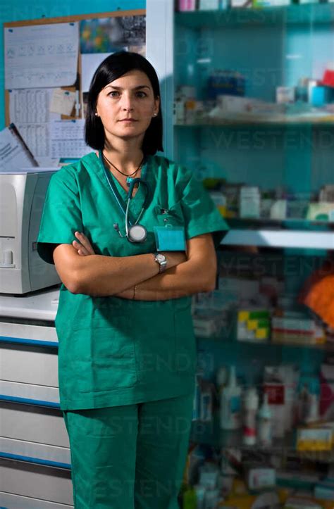 Portrait of female surgeon wearing scrubs standing in operating theatre ...