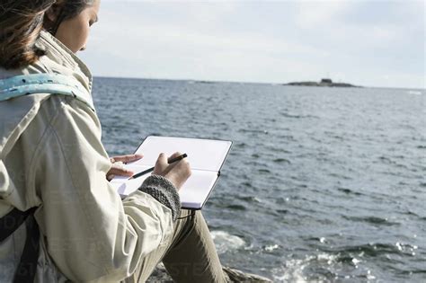 Teenage girl writing letter at seaside stock photo