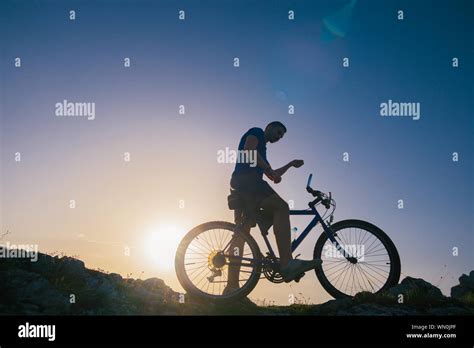 Strong fit male mountain biker performing stunts on rocky terrain on a ...