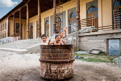 Tajik children playing in drum of water outside mosque by Damon Lynch / 500px