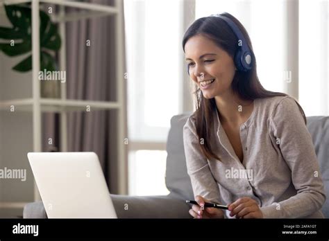 Smiling girl in wireless headphones working at laptop Stock Photo - Alamy