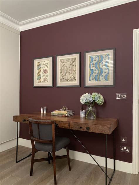 a wooden desk sitting in front of a wall with two pictures on top of it