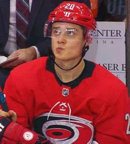 a hockey player wearing a red jersey and glasses