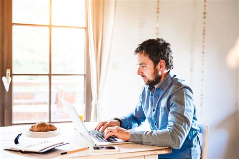 Man sitting at desk working from home on laptop - Man sitting at the ...