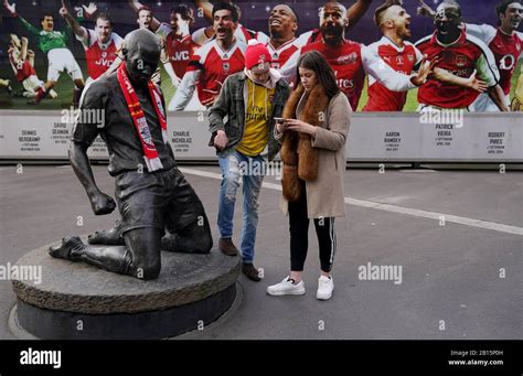 Arsenal fans stand near the Thierry Henry statue outside the ground ...