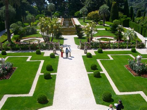 two people are standing in the middle of a garden with many trees and ...