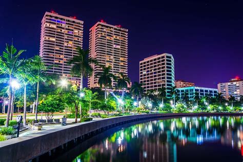 Palm trees along the Intracoastal Waterway and the skyline at night in West Palm Beach, Florida ...