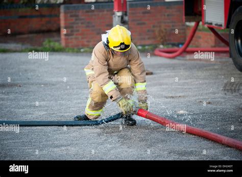 Firefighter un-coupling fire hose Stock Photo - Alamy