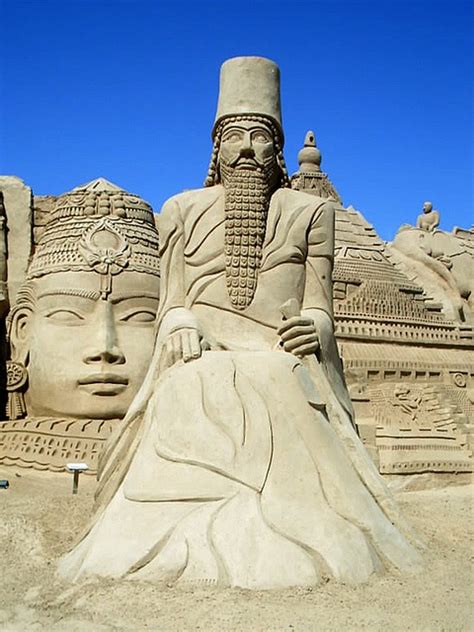 a sand sculpture of a man sitting in front of two heads