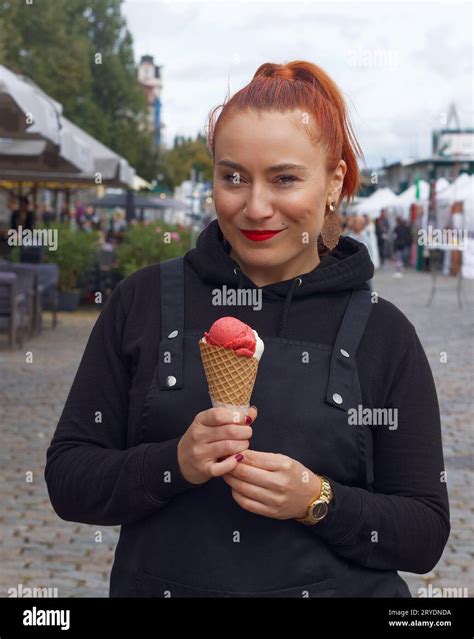 Pretty young smiling woman posing with an ice cream cone at the farmers market in the centre of ...