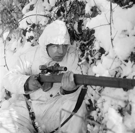 A British 6th Airborne Division sniper on patrol in the Ardennes, wearing a snow camouflage suit ...