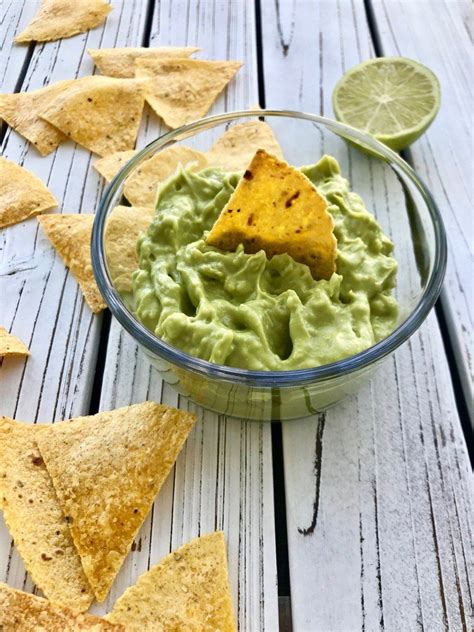 a glass bowl filled with guacamole and tortilla chips