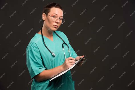Free Photo | Female nurse in green uniform holding the blank and writing history.