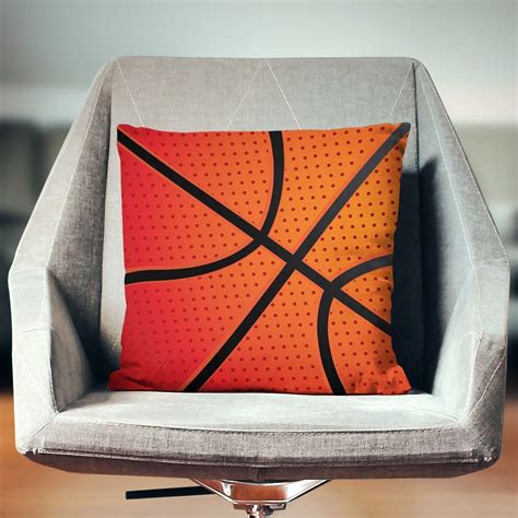 an orange and black basketball pillow sitting on top of a gray chair in front of a wooden floor