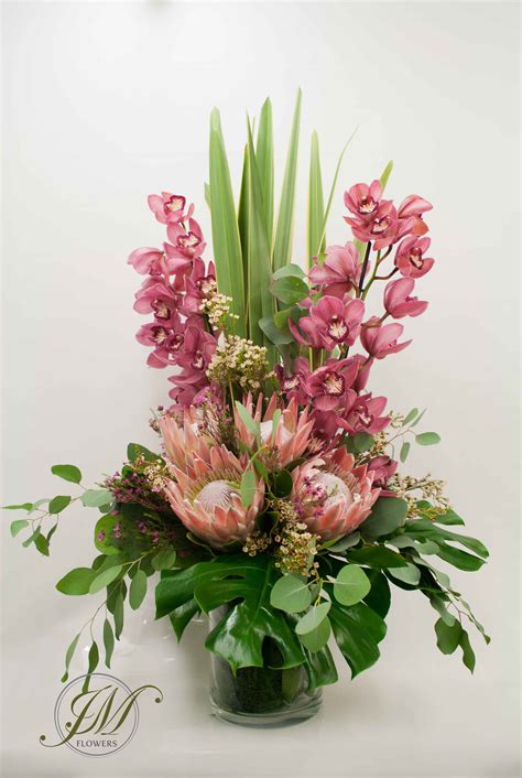 Tall vase display made of cymbidium orchids, proteas, wax flowers and ...