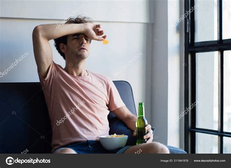 Young man watching tv on the couch. Stock Photo by ©nicomenijes 311941976