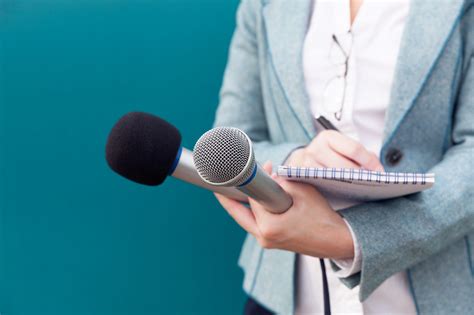 News reporter or TV journalist at press conference, holding microphone and writing notes ...