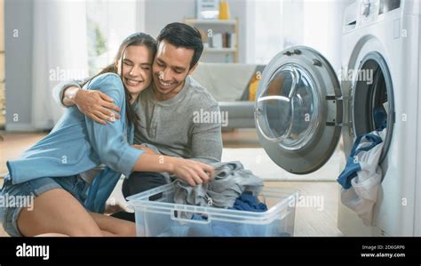 Beautiful Young Couple Sit Next to a Washing Machine at Home. They ...