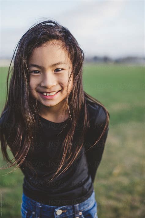 «Cute Elementary School Aged Asian Girl Happy In Windy Field» del colaborador de Stocksy «Rob ...