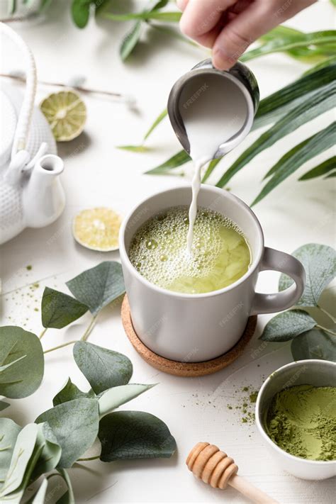 Free Photo | Green tea latte with milk in a white cup with green leaves and wooden spoon