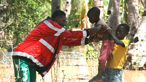 A Kenya Red Cross volunteer helps evacuate boys after heavy rains in ...