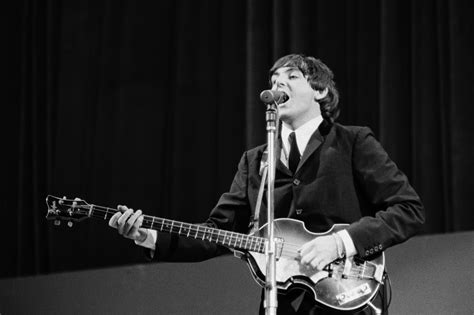 a man in a suit and tie playing a guitar while standing next to a microphone