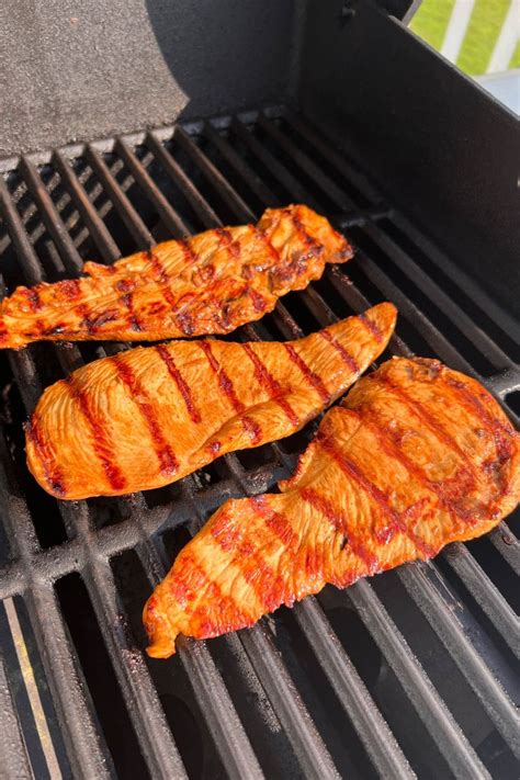 three pieces of meat cooking on a grill