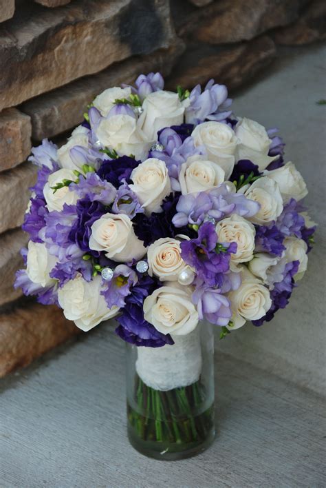 a bouquet of white and purple flowers sitting in a glass vase on the ...