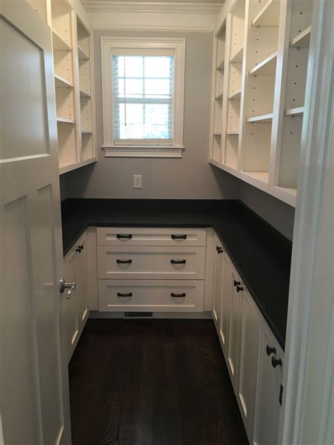 Large walk-in pantry with white shaker cabinets and honed dark granite ...