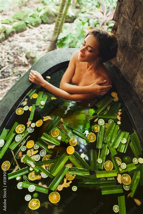 Beautiful young woman enjoying in outdoor spa. Luxury stone bath tub ...