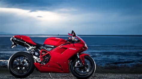 a red motorcycle parked next to the ocean