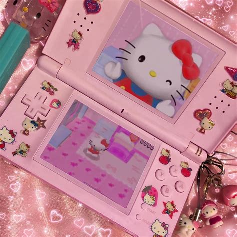 two hello kitty laptops sitting on top of a pink surface with hearts ...