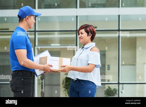 Vietnamese delivery man giving packages to smiling woman Stock Photo ...