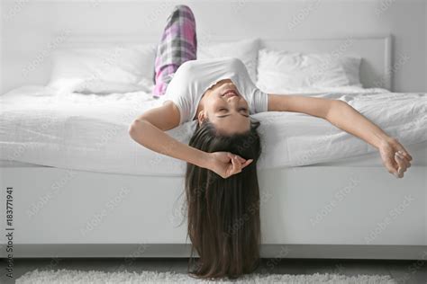 Young woman lying upside down in bed at home Stock Photo | Adobe Stock