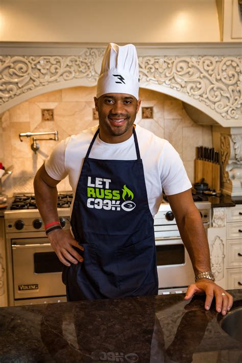 Russell Wilson Trades the Field For the Kitchen with “Let Russ Cook” Apron to Fight Hunger ...