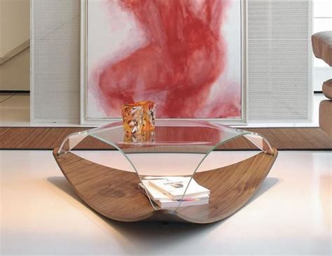 a glass and wood coffee table with a book on it in front of a painting